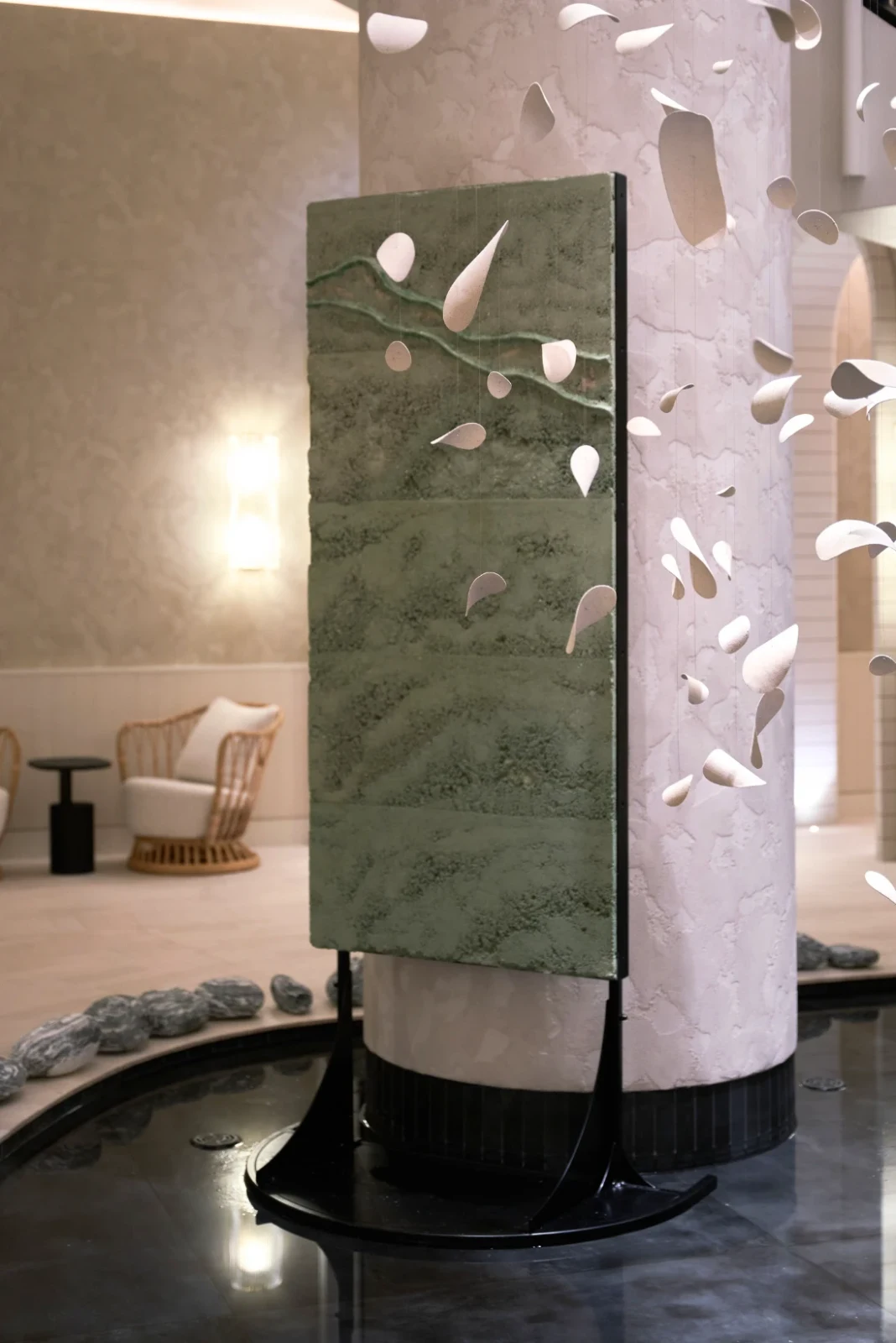 Terre Verte by Adam Weismann seen at an angle on its black stand, with white suspended petals in front