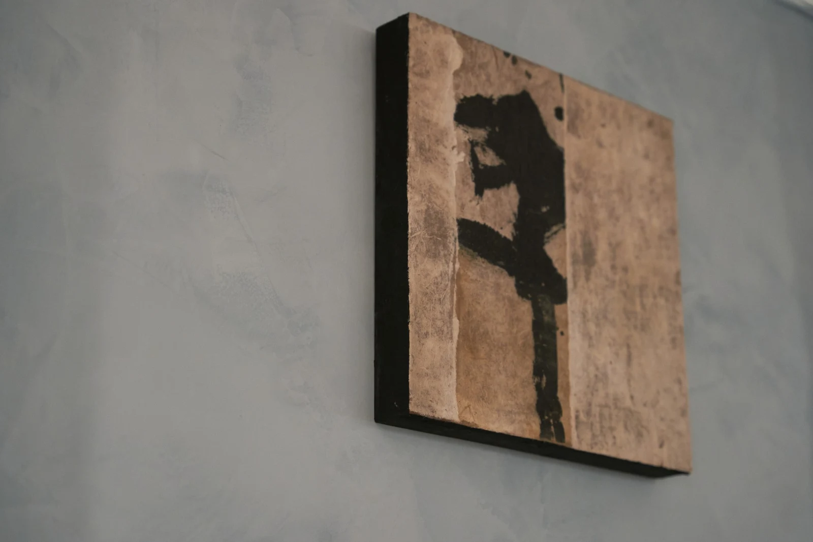 Untitled (GES#4) by Alexandra Yan Wong, seen at an angle on a blue plaster wall, showing the canvas edge