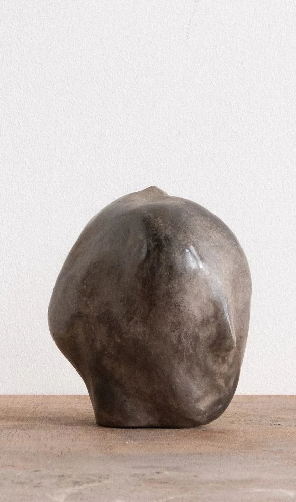 All Our Gods Are Dancing Gods by Arran Gregory, a smooth grey burnished clay head with a pointed crown, its face turned to the right