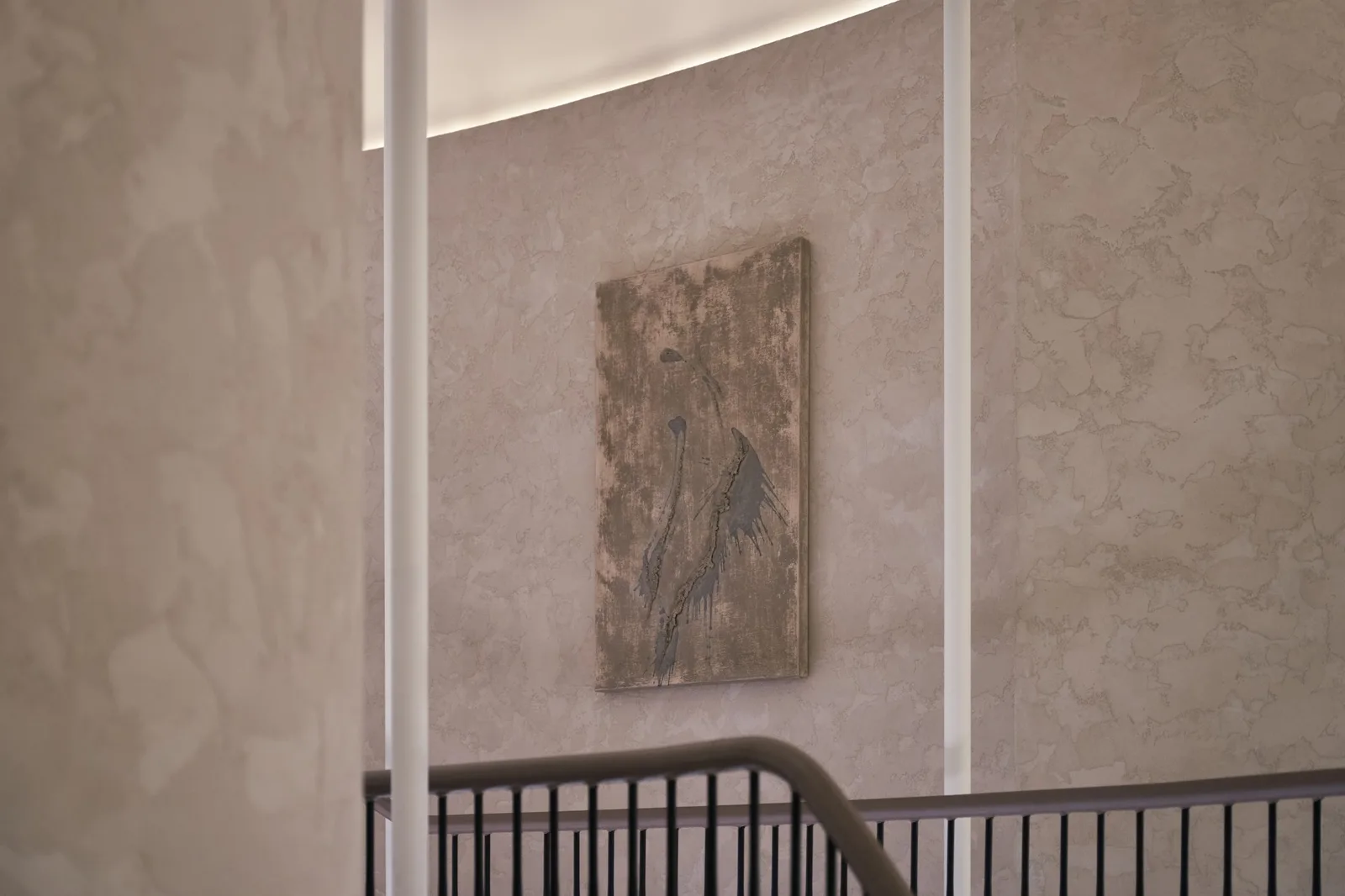 Unearthing Series #1 by Eleanor Herbosch hanging on a curved plaster wall above a stairwell with a dark handrail
