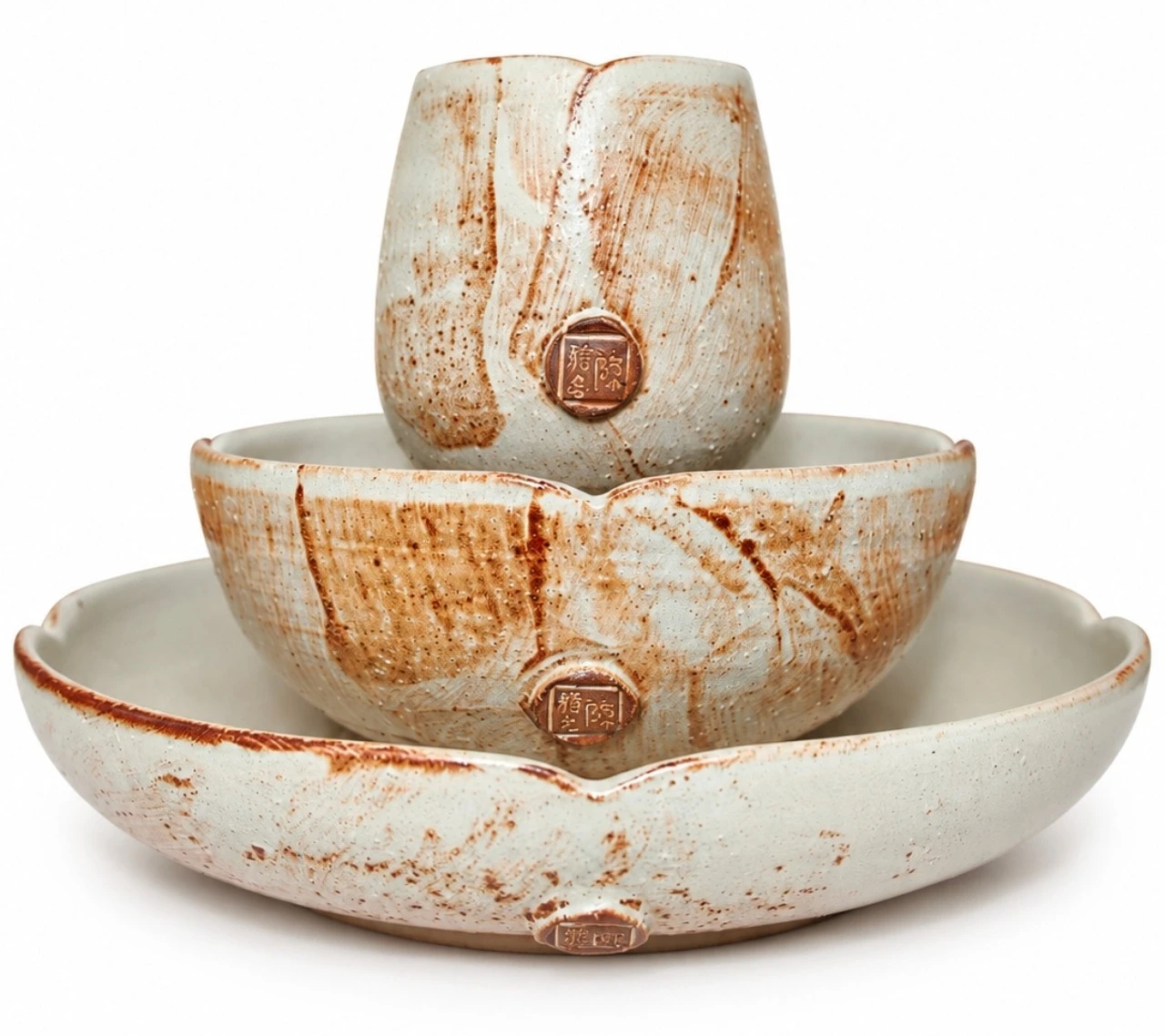 Lotus Set by Jacob Chan, a cup stacked in a bowl on a petal-rimmed plate, all in cream glaze with rust brushwork