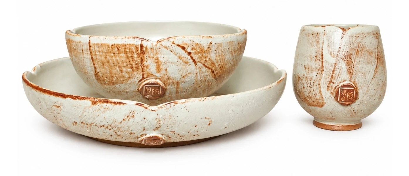 Lotus Set by Jacob Chan, a petal-rimmed plate and bowl in cream glaze with rust brushwork beside a matching cup