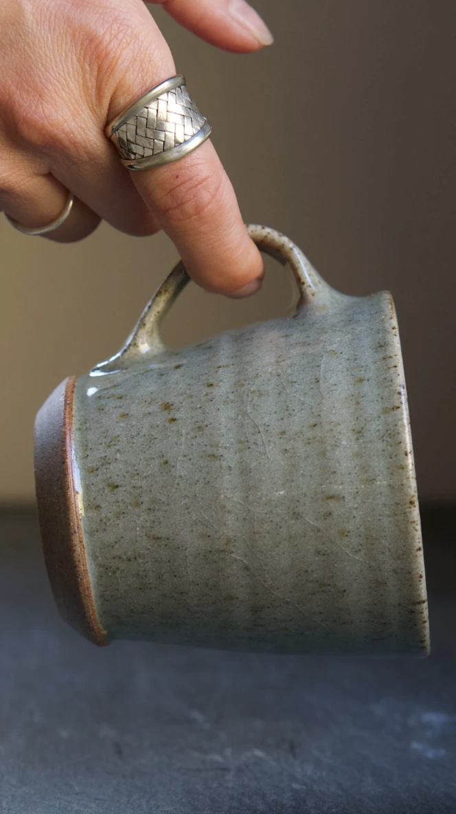 A hand holding the handle of Lucia Ocejo's Mug
